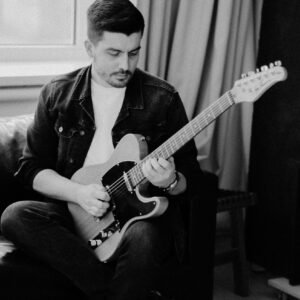 Grayscale Photo of Bearded Man Playing Electric Guitar